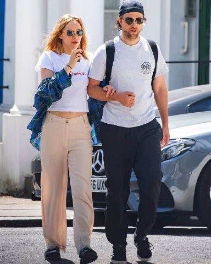 *EXCLUSIVE* London, UNITED KINGDOM - Braless Suki Waterhouse spotted smoking an E-cigarette whilst walking with beau Robert Pattinson. The pair were spotted strolling in London looking loved up as they walk arm in arm. Suki was wearing a crop t shirt with Realistation printed on it and flared beige trousers. Whilst Robert sported his signature cap worn backwards and white t-shirt and baggy trousers. Pictured: Suki Waterhouse, Robert Pattinson BACKGRID USA 21 JULY 2020 USA: +1 310 798 9111 / UK: +44 208 344 2007 / *UK Clients - Pictures Containing Children Please Pixelate Face Prior To Publication* *CLIENT RESTRICTION APPLIED*