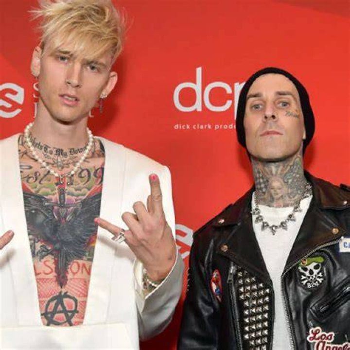 Machine Gun Kelly and Travis Barker holding signs