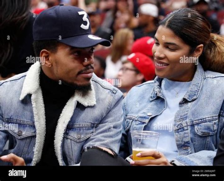 Musician Chance the Rapper, left, kisses his girlfriend Kirsten Corley while attending a preseason NBA basketball game between the Chicago Bulls and the New Orleans Pelicans Sunday, Oct. 8, 2017, in Chicago. (AP Photo/Jim Young)