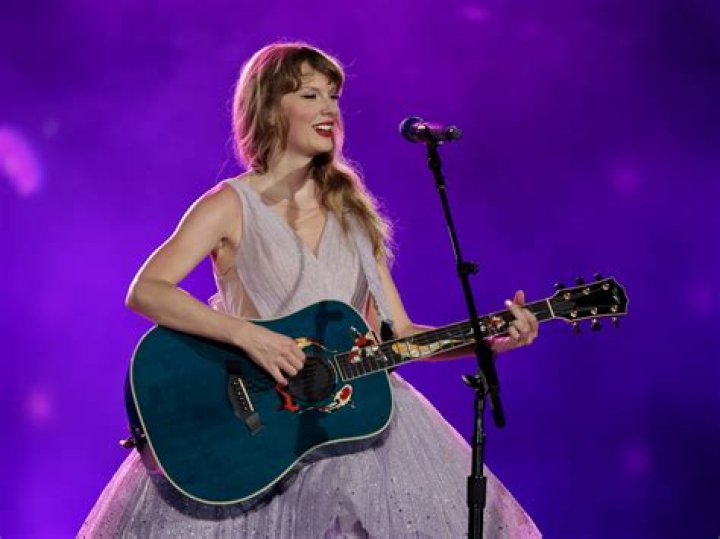 Taylor Swift playing guitar on her Eras Tour